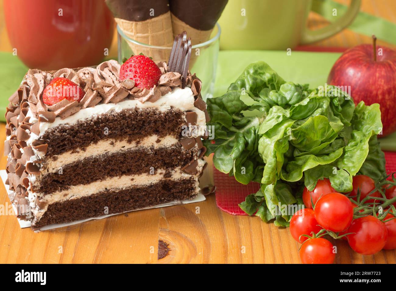 Schokoladenkuchen versus Salat und Apfel bei der Wahl der gesunden Ernährung Stockfoto