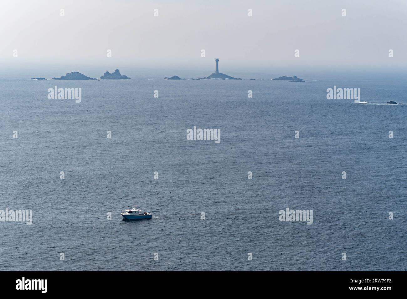 Fischerboot segelt vorbei am Leuchtturm und felsigen Inselchen vor der Küste Cornwalls Stockfoto