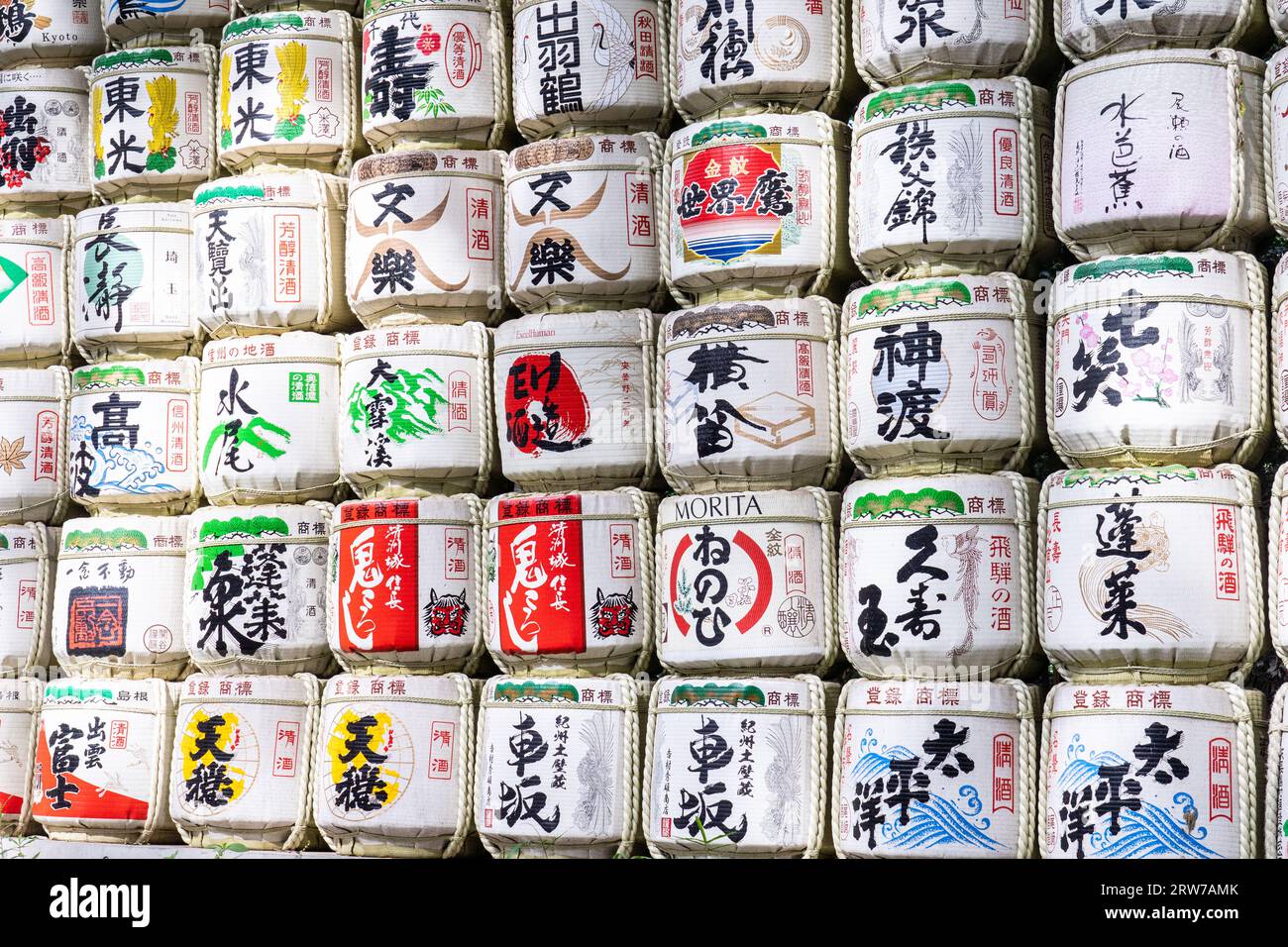 Stapel von bunten japanischen Sake-Fässern, die von Destillatoren am Südeingang des Meiji Jingu in einem 170 Hektar großen Wald in Shibuya, Tokio, Japan, gespendet wurden. Der Shinto-Schrein ist den Geistern von Kaiser Meiji und seiner Frau, Kaiserin Shoken, gewidmet. Stockfoto