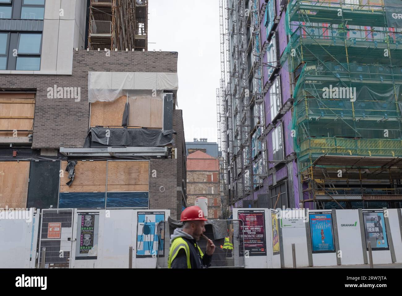 Ein Bauarbeiter läuft mit einer Eislutsche während einer Pause an der Argyll Street, Glasgow vorbei. Gerüste und Konstruktionstechniken sind sichtbar. Stockfoto