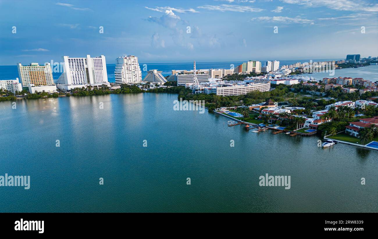 Genießen Sie den atemberaubenden Blick auf Hotels und Residenzen entlang der Nichupté Lagune am Tag. Das ruhige Wasser spiegelt die Architektur wider und schafft ein wunderschönes Ref Stockfoto