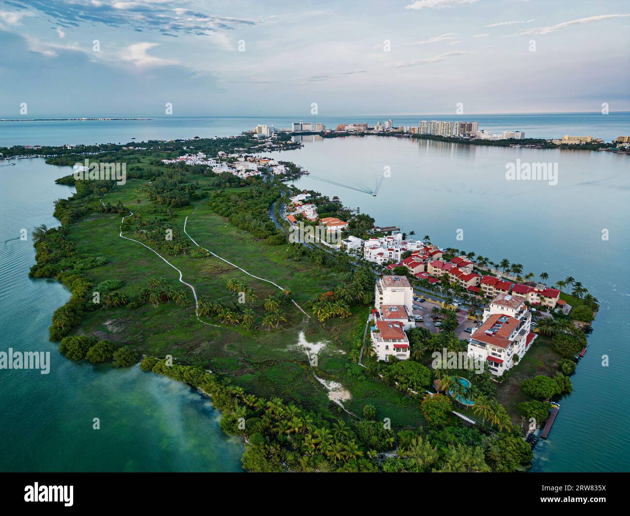 Genießen Sie den atemberaubenden Blick auf die Hotels und Residenzen an der Nichupté Lagune am Tag. Das ruhige Wasser spiegelt die Architektur wider und schafft ein wunderschönes Ref Stockfoto