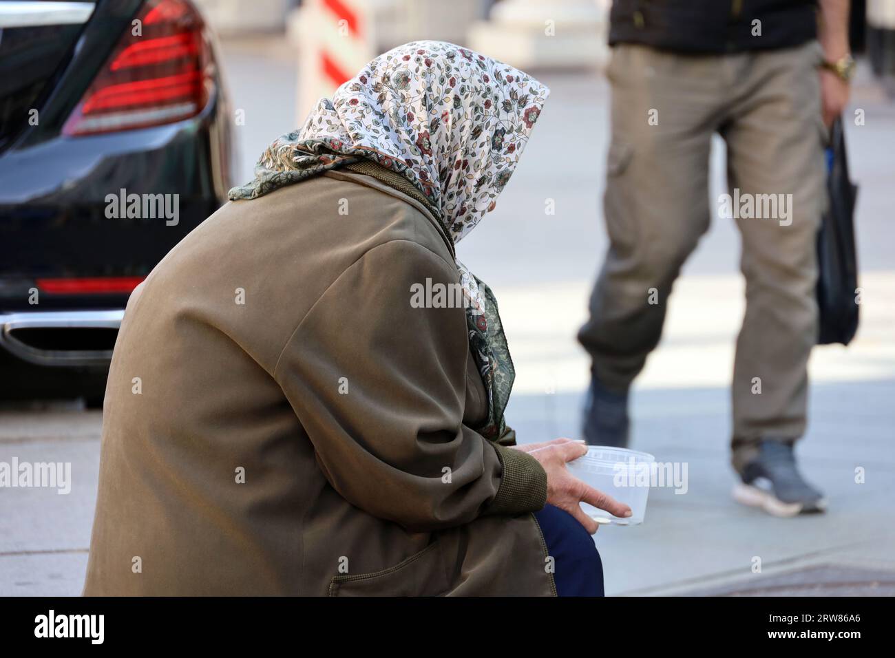 Bettlerin bittet um Almosen, die auf einer Straße sitzen. Armut, Obdachlosigkeit und Betteln Stockfoto