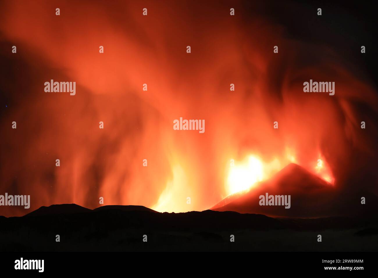 Etna durante suggestiva eruzione di notte dal cratere del vulcano con volti e forme immaginarie creati dalle emissioni di fumo. Agosto 2023 Stockfoto