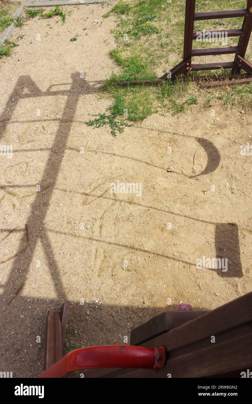 Schatten von zwei Schaukeln auf dem Sand auf dem Spielplatz. Blick von oben auf den Spielkomplex. Stockfoto