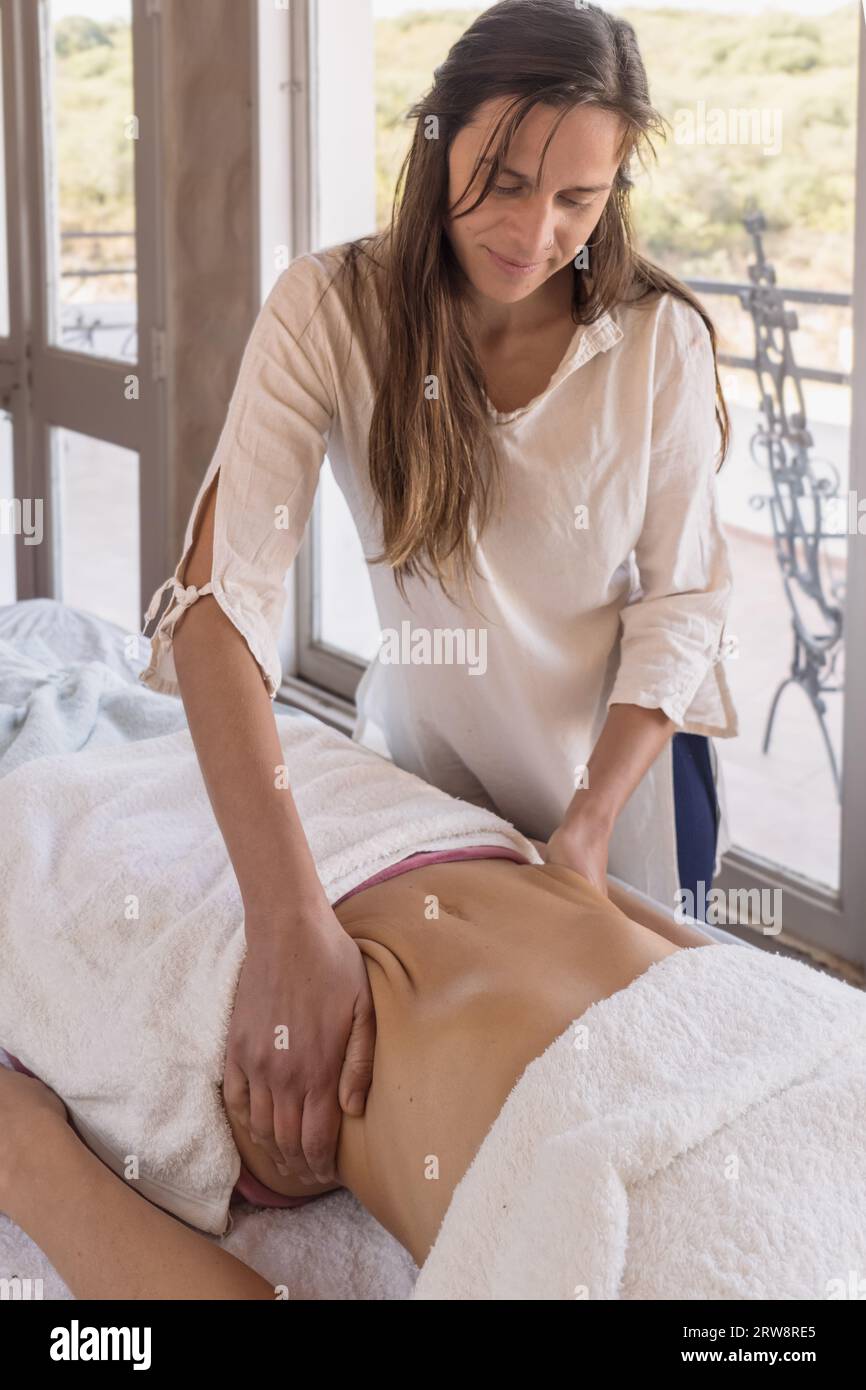 Junge Frau Therapeutin, die entspannende und formende Massage auf dem Bauch des Patienten, manuelle und ästhetische Verfahren, Hände Massage Bauch im Spa-Salon. Stockfoto