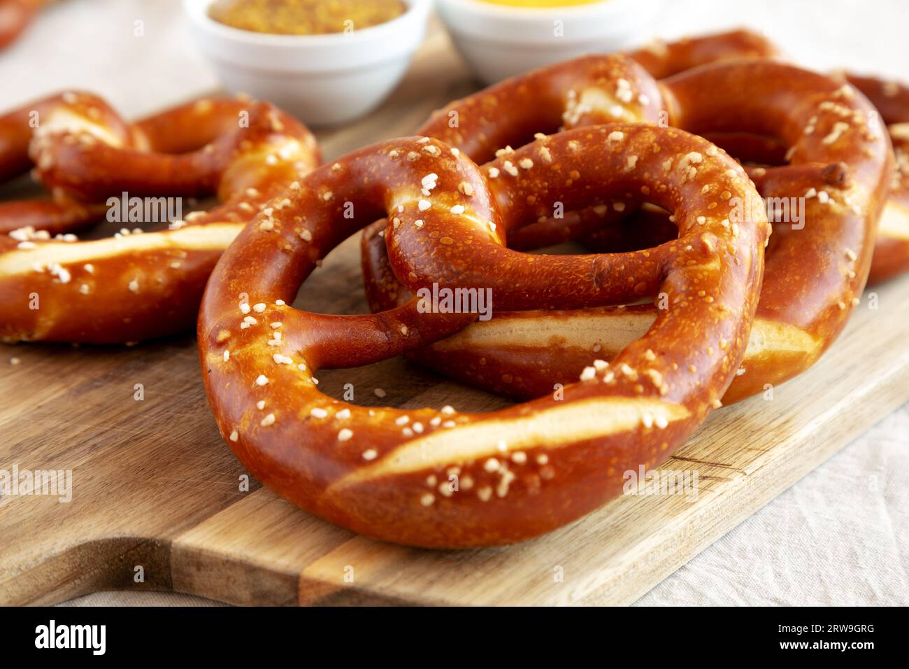 Hausgemachte weiche bayerische Brezeln mit Senf auf Holzbrett, Seitenansicht. Stockfoto