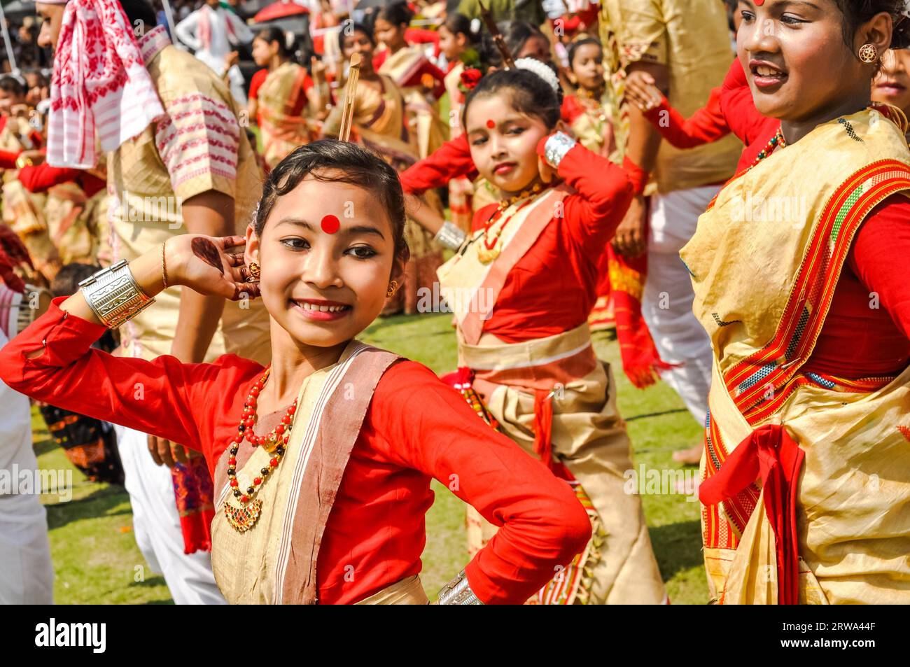 Guwahati, Assam, um April 2012: Junges einheimisches Mädchen in rotem und gelbem Sari mit rotem Punkt auf der Stirn beim Tanz beim traditionellen Bihu-Festival in Stockfoto