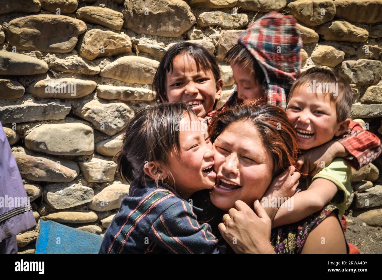 Dolpo, Nepal, um Juni 2012: Kleine Kinder umarmen ihre Mutter und lächeln freudig vor der Fotokamera in Dolpo, Nepal. Dokumentarisches Editorial Stockfoto