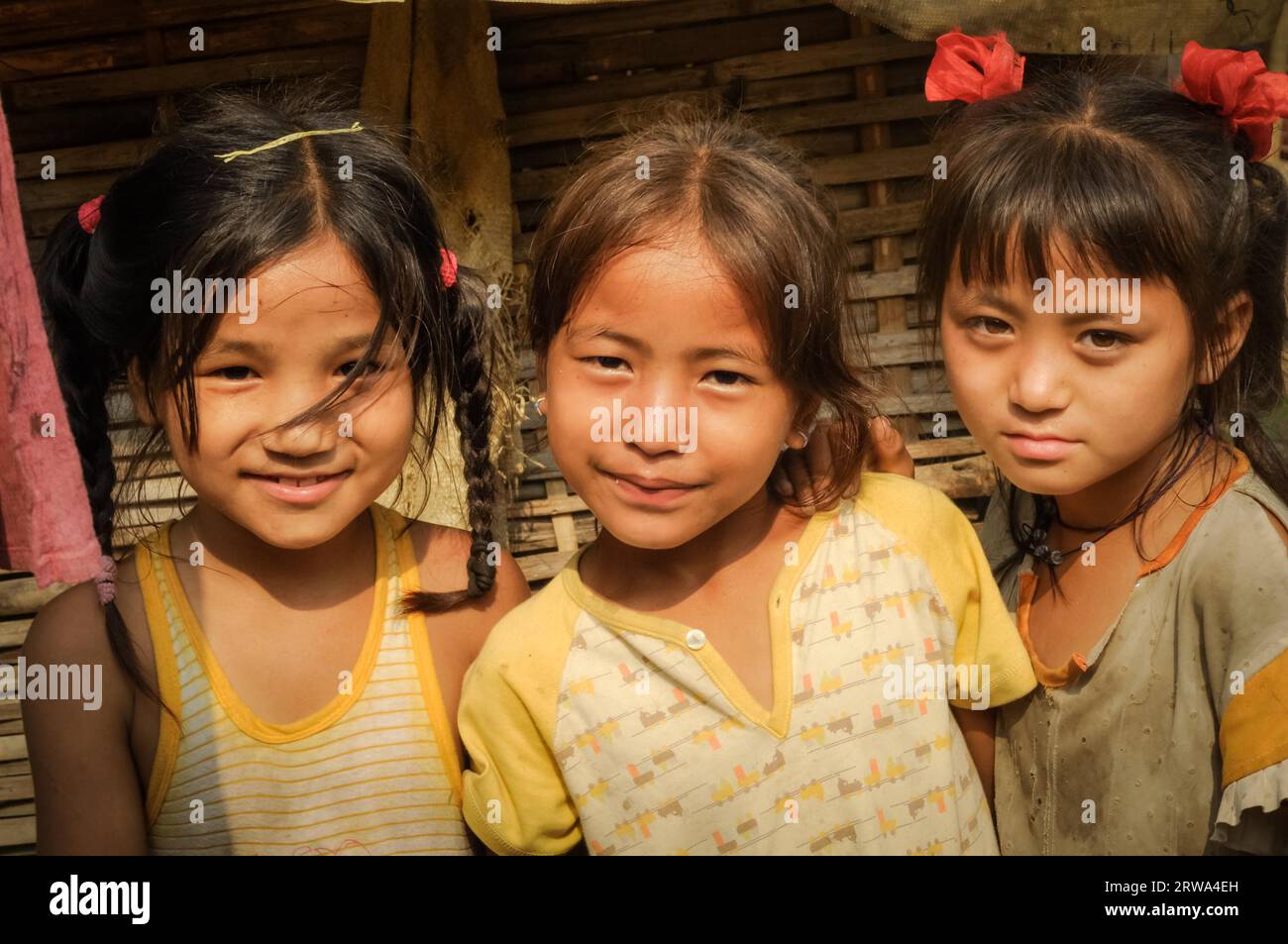 Damak, Nepal, um Mai 2012: Foto von drei jungen Mädchen in gelben T-Shirts, die nebeneinander und im nepalesischen Flüchtlingscamp in Damak, Nepal, stehen. Stockfoto