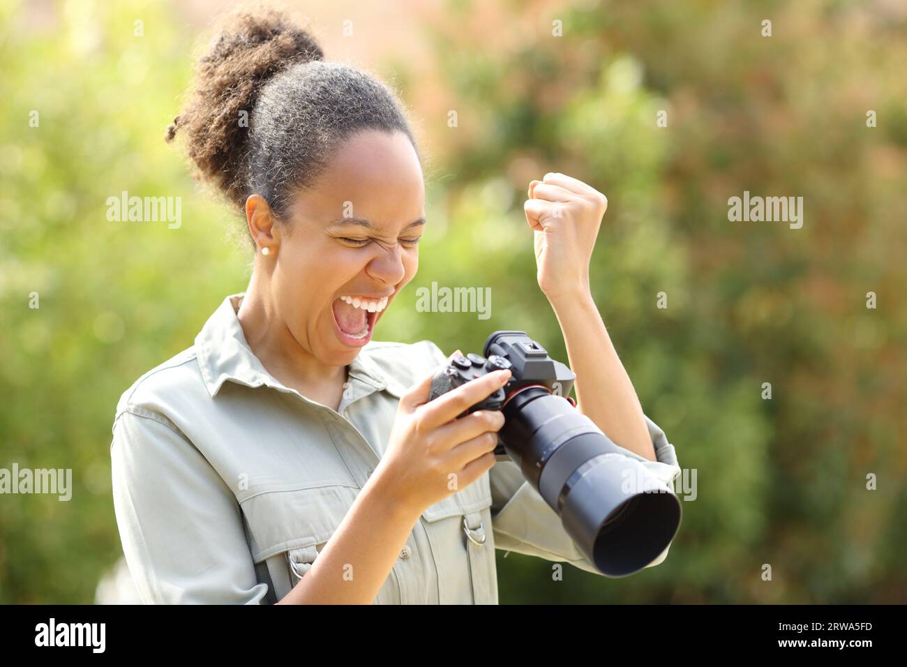 Aufgeregter schwarzer Fotograf, der im Park ein gutes Ergebnis überprüft Stockfoto