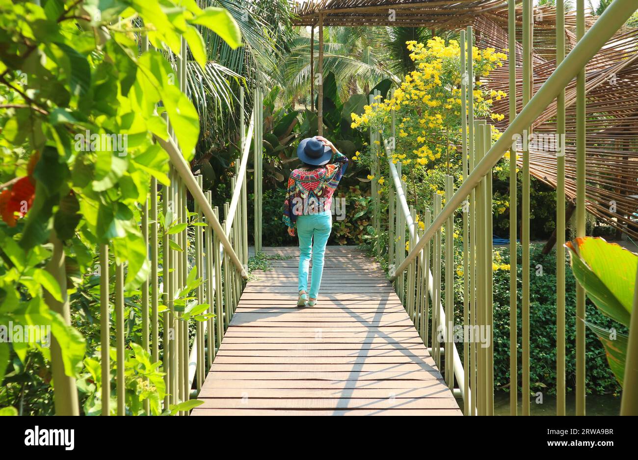 Frau, die glücklich auf einer Brücke im sonnigen Garten läuft Stockfoto