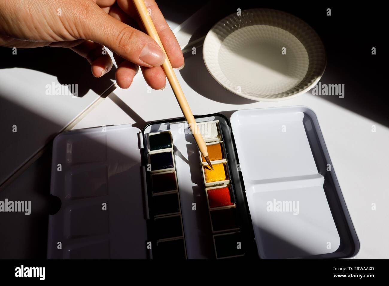 Aquarellpinsel in Hand und professionelle Farben Stockfoto