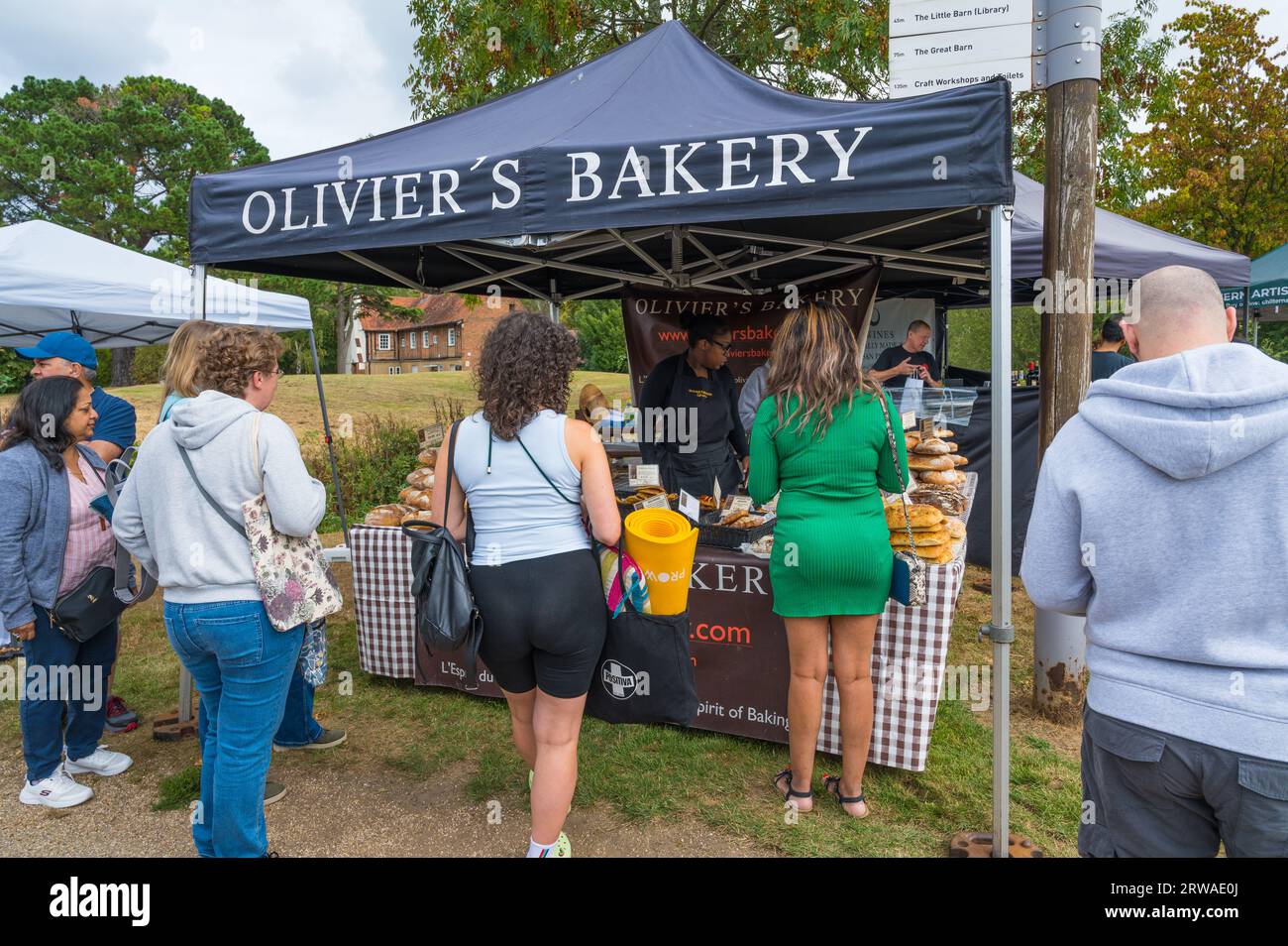 Kunden, die Brot, Kuchen und Gebäck von Olivier's Bakery am Handwerks- und Lebensmittelmarkt Duckpond Market kaufen. Ruislip, Middlesex, England, Großbritannien Stockfoto
