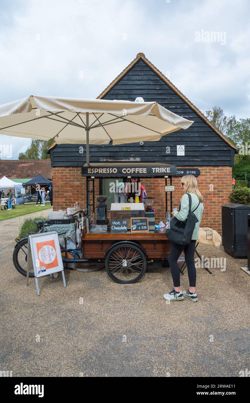 Ruislip Duckpond Market, Lebensmittel- und Kunsthandwerksmarkt, der monatlich stattfindet. Junge Frau, die Kaffee vom Espresso Coffee Trike kauft. Middlesex England Vereinigtes Königreich. Stockfoto