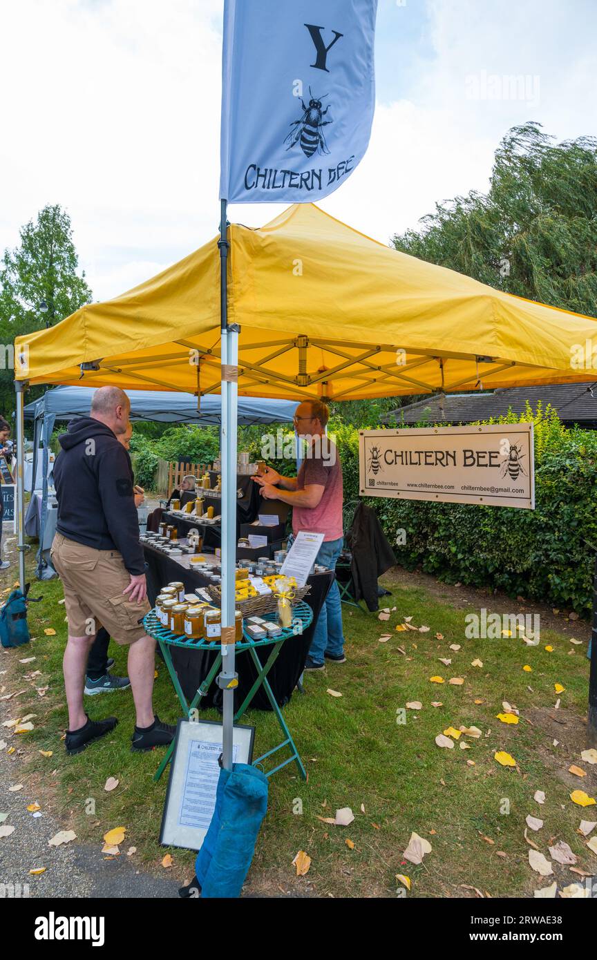 Ruislip Duckpond Market Kunsthandwerksmarkt. Chiltern Bee Stall verkauft Honig- und Bienenwachsprodukte. Standhalter im Gespräch mit dem Kunden. England Großbritannien. Stockfoto
