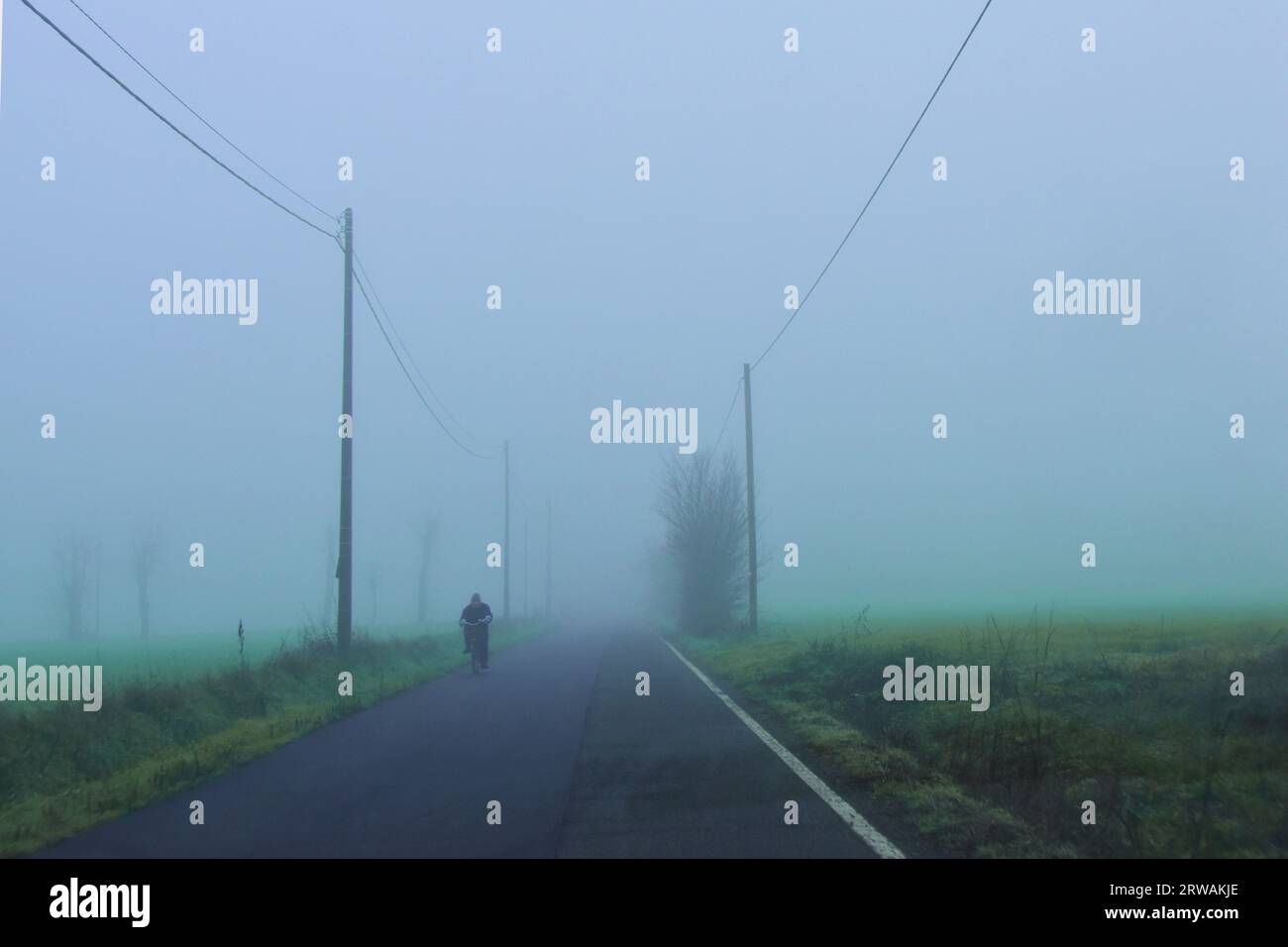 Nicht erkennbare Person, die auf einer Straße in Fog, Lobbi, Piemont, Italien radelt Stockfoto