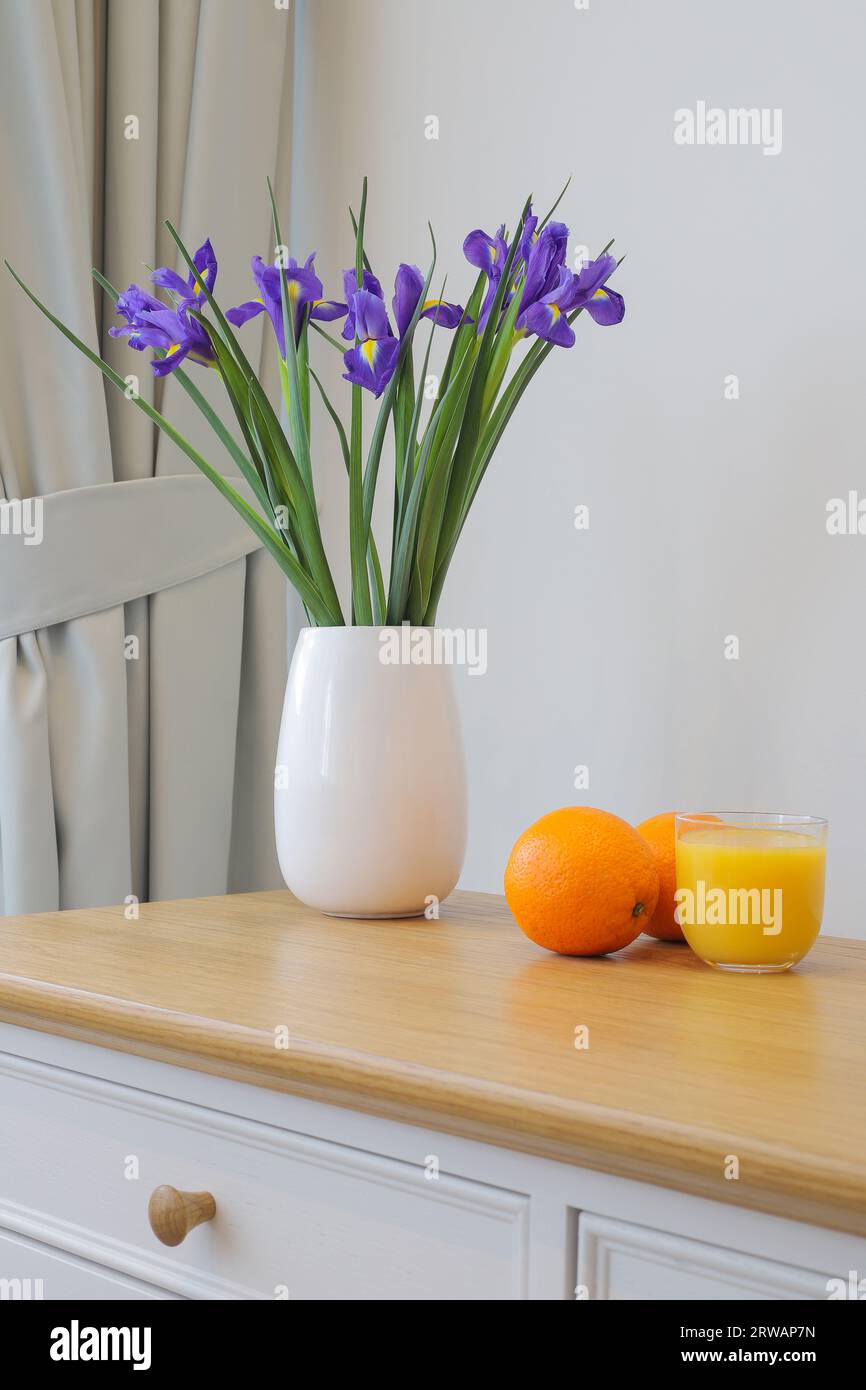 Blüht niederländische Iris in der Vase und Orangensaft Stockfoto