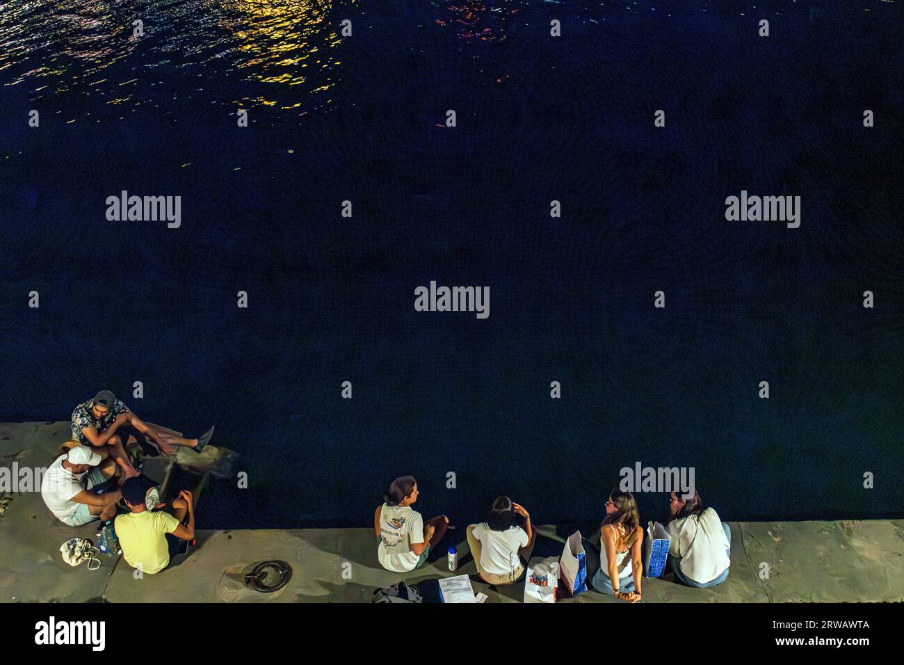 Eine Gruppe von Freunden sitzt nachts am Fluss Saone in Lyon. Stockfoto