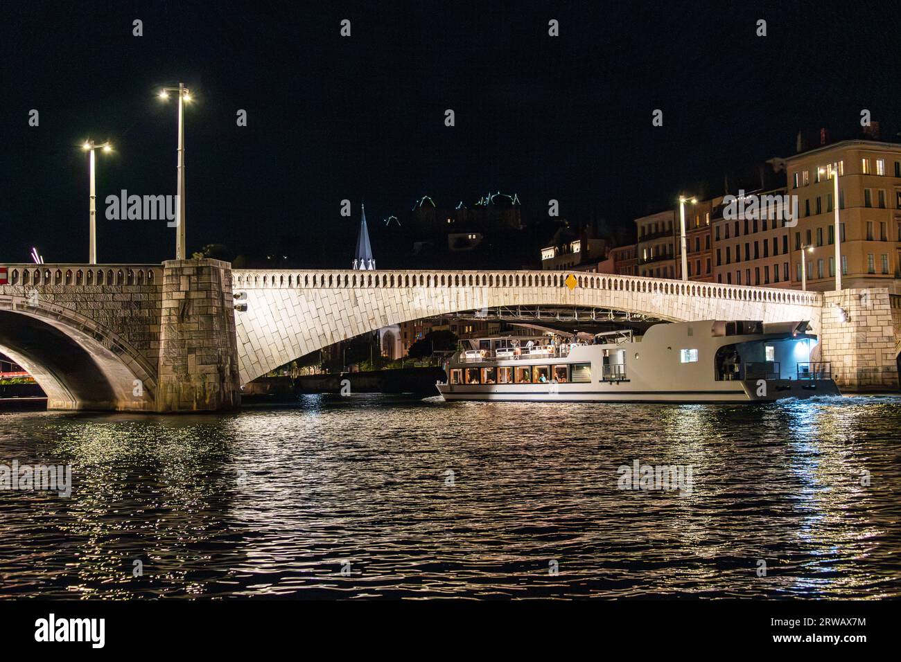 Ein Boot auf dem Bateaux Lyonnais führt nachts unter der Pont Bonaparte in Lyon, Rhonealpen, Frankreich. Stockfoto