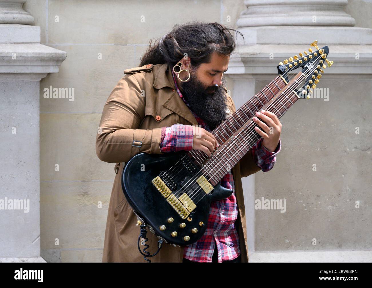 London, Großbritannien. Busker am Trafalgar Square, der eine 16-saitige E-Gitarre spielt Stockfoto