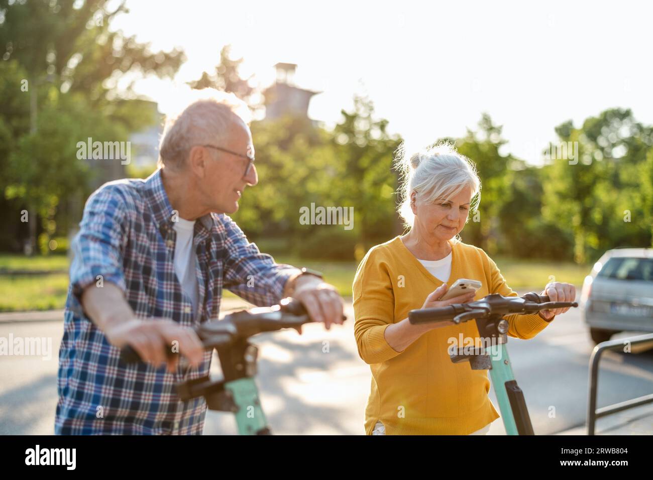 Ein älteres Paar, das in der Stadt Elektroroller fährt Stockfoto