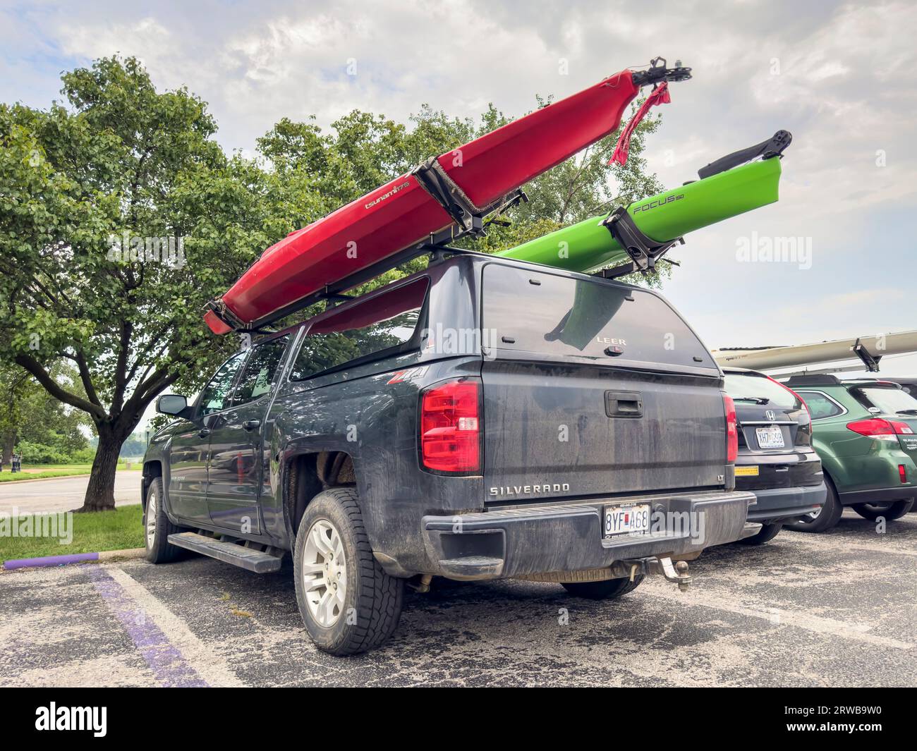 St Charles, MO, USA - 4. August 2023: Kajaks auf Dachgepäckträgern von Chevy Silverado Truck mit leerer Kappe geparkt unter anderen Autos. Stockfoto