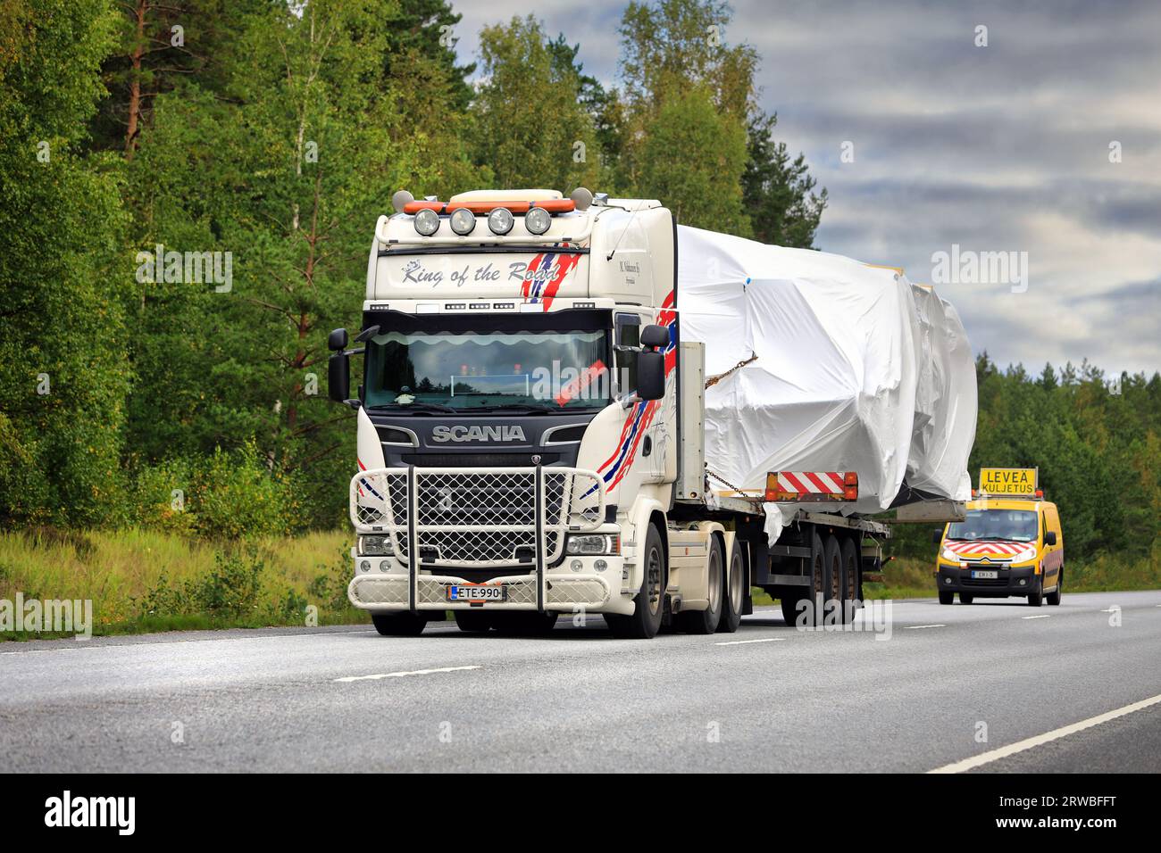 Der Scania R580-Lkw-Tieflader transportiert breite Lasten in Richtung Hafen von Hanko. Der Transport verfügt über Pilotfahrzeuge vorn und hinten. Raasepori, Finnland. September 23 Stockfoto