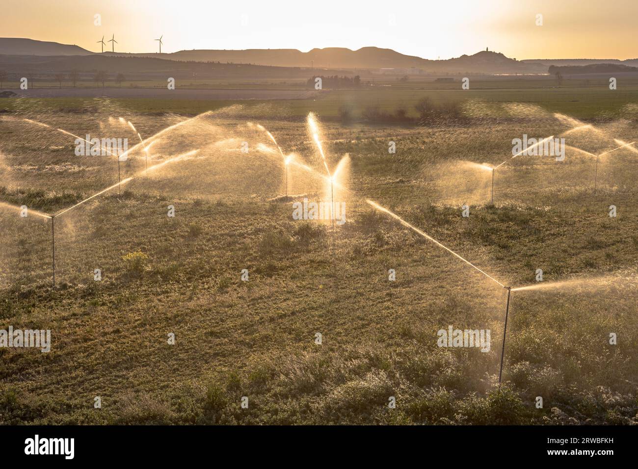 Bewässerungssprinkler, die Ackerland bei Sonnenuntergang in Huesca, Spanien, wässern. Stockfoto