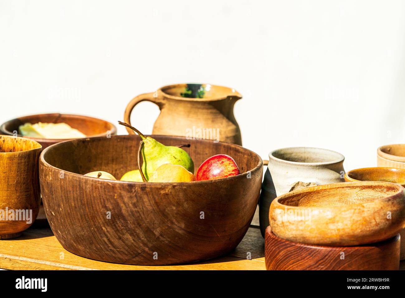 Mittelalterliche Nachstellung, ein Tisch mit Obst und Getränken vor einem weißen Hintergrund. Holzschale mit Äpfeln und Birnen, verschiedene andere Tassen und Schüsseln Stockfoto