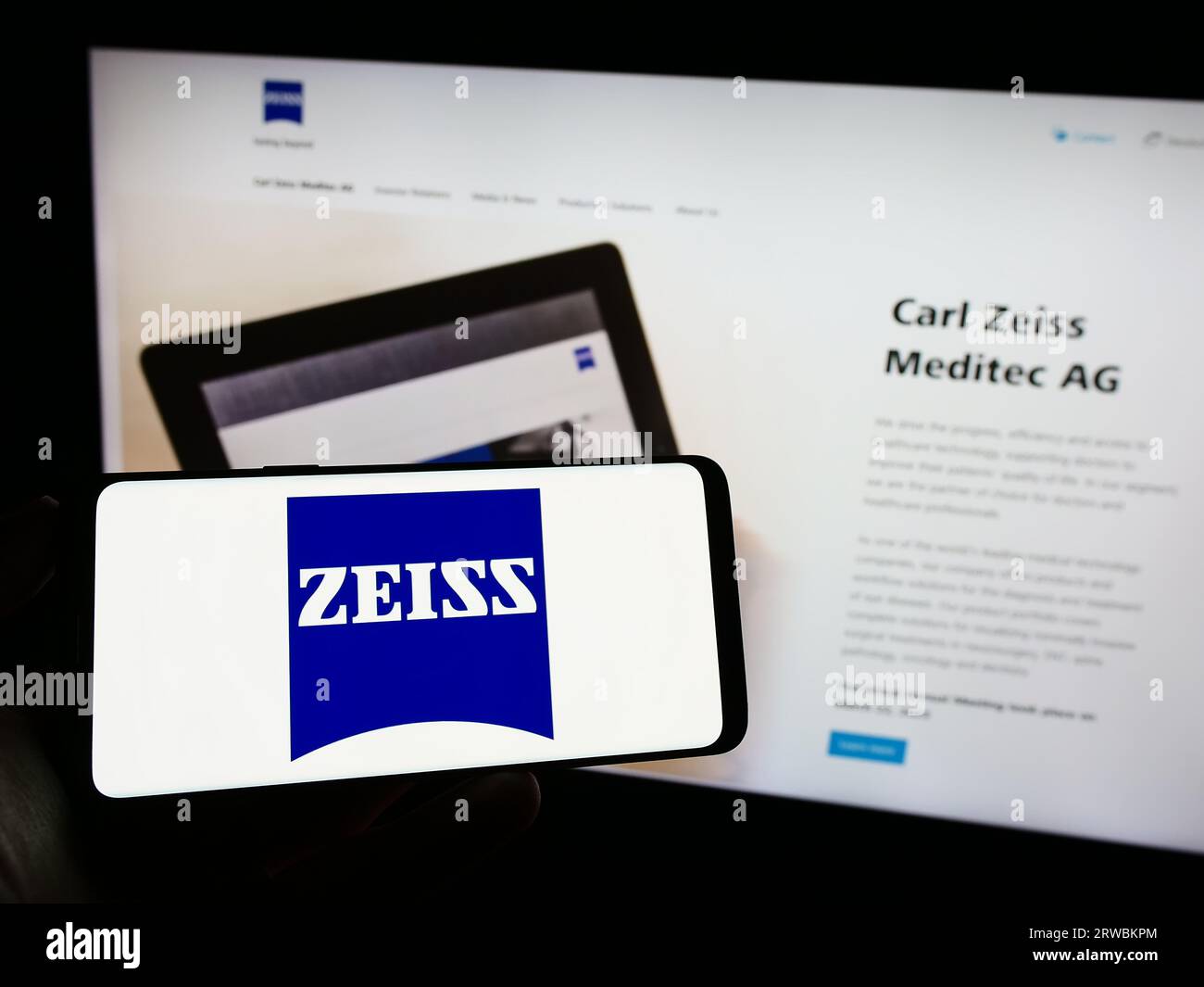 Person, die ein Mobiltelefon mit Logo des Medizintechnikunternehmens Carl Zeiss Meditec AG auf dem Bildschirm vor der Webseite hält. Konzentrieren Sie sich auf das Display des Telefons. Stockfoto