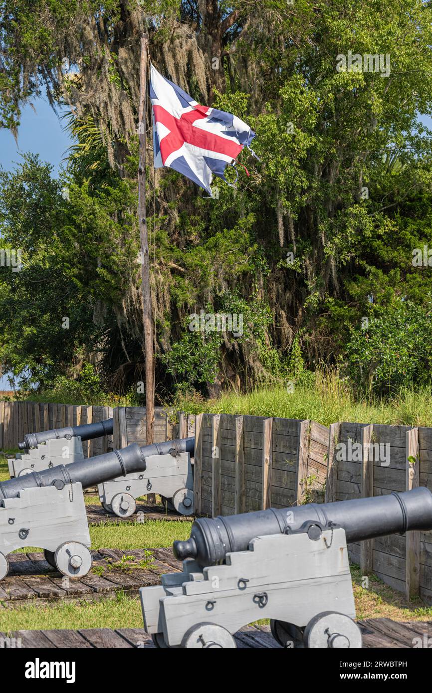 Zerrissene britische Flagge, die über Kanonen wehte, im wiederaufgebauten Fort King George aus dem 18. Jahrhundert am Altamaha River in Darien, Georgia. (USA) Stockfoto