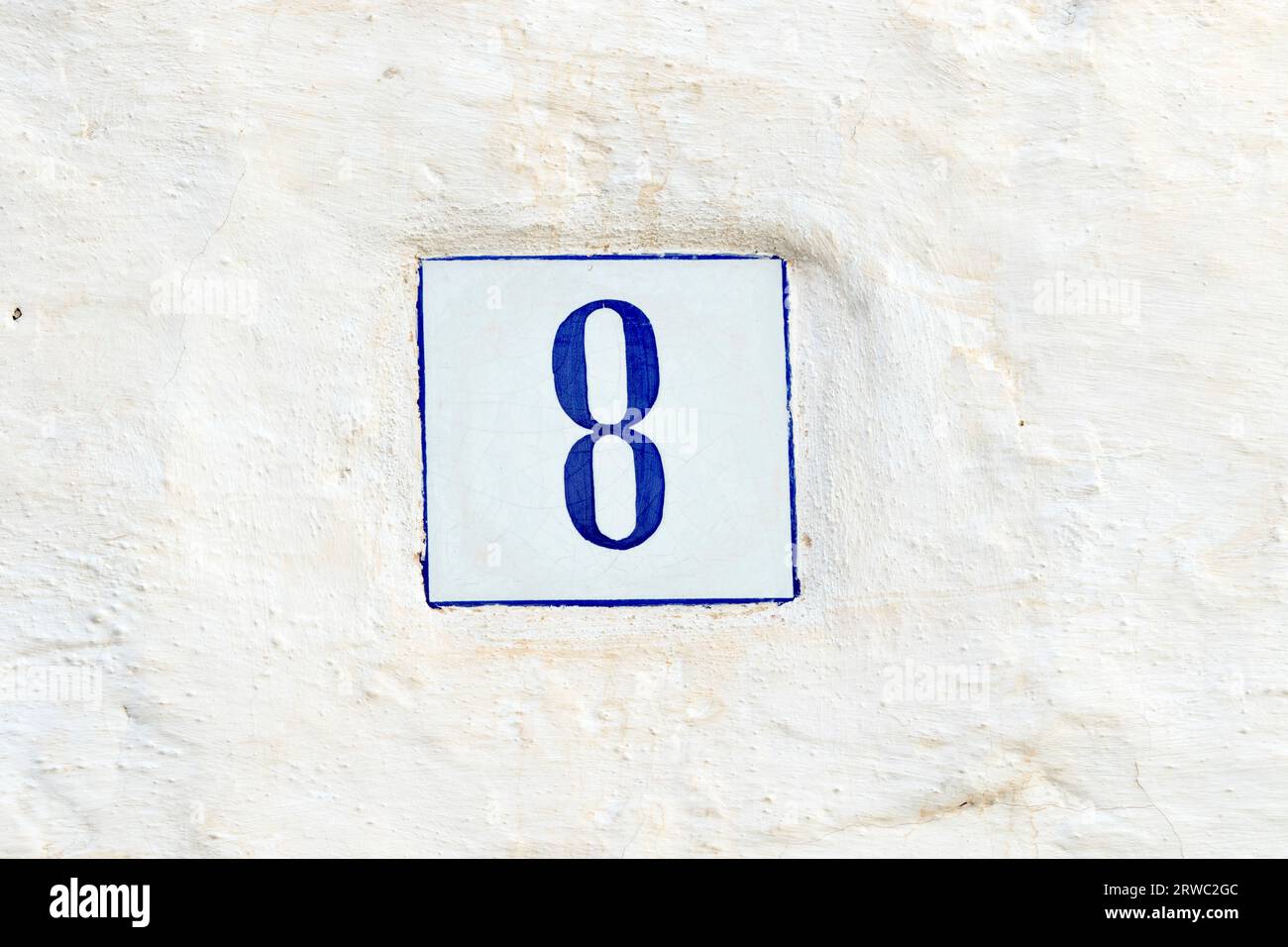 Blaue Hausnummer 8 an einer weißen Wand Stockfoto
