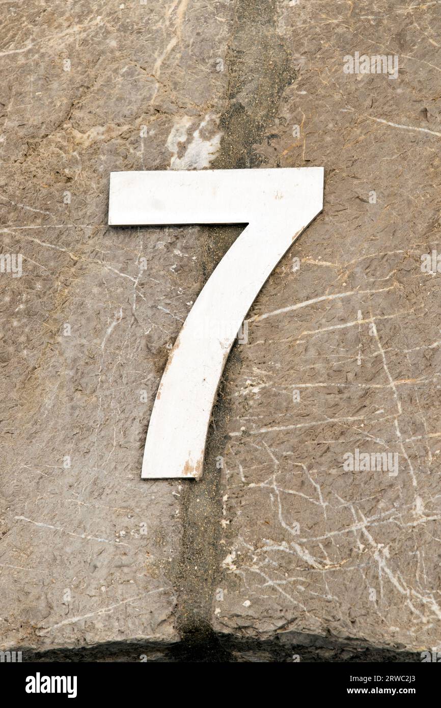 Weiße Nummer Sieben Hausnummer auf einer Steinmauer Stockfoto