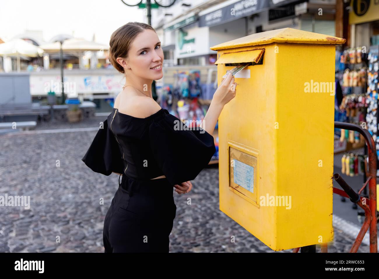 Junge schöne Frau, die Briefe auf der Straße postet Stockfoto