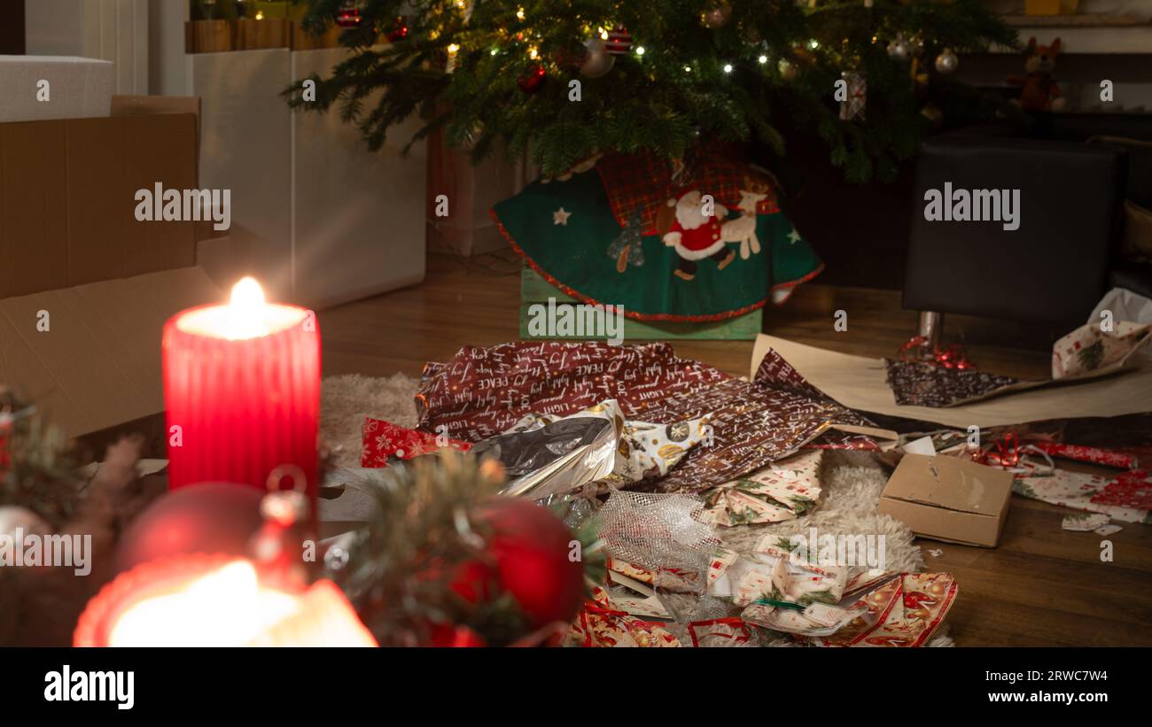Es ist Heiligabend. Die Geschenke wurden ausgepackt. Im weihnachtlichen Wohnzimmer herrscht ein Chaos aus Geschenkpapier und Boxen unter der Weihnachts-tr Stockfoto