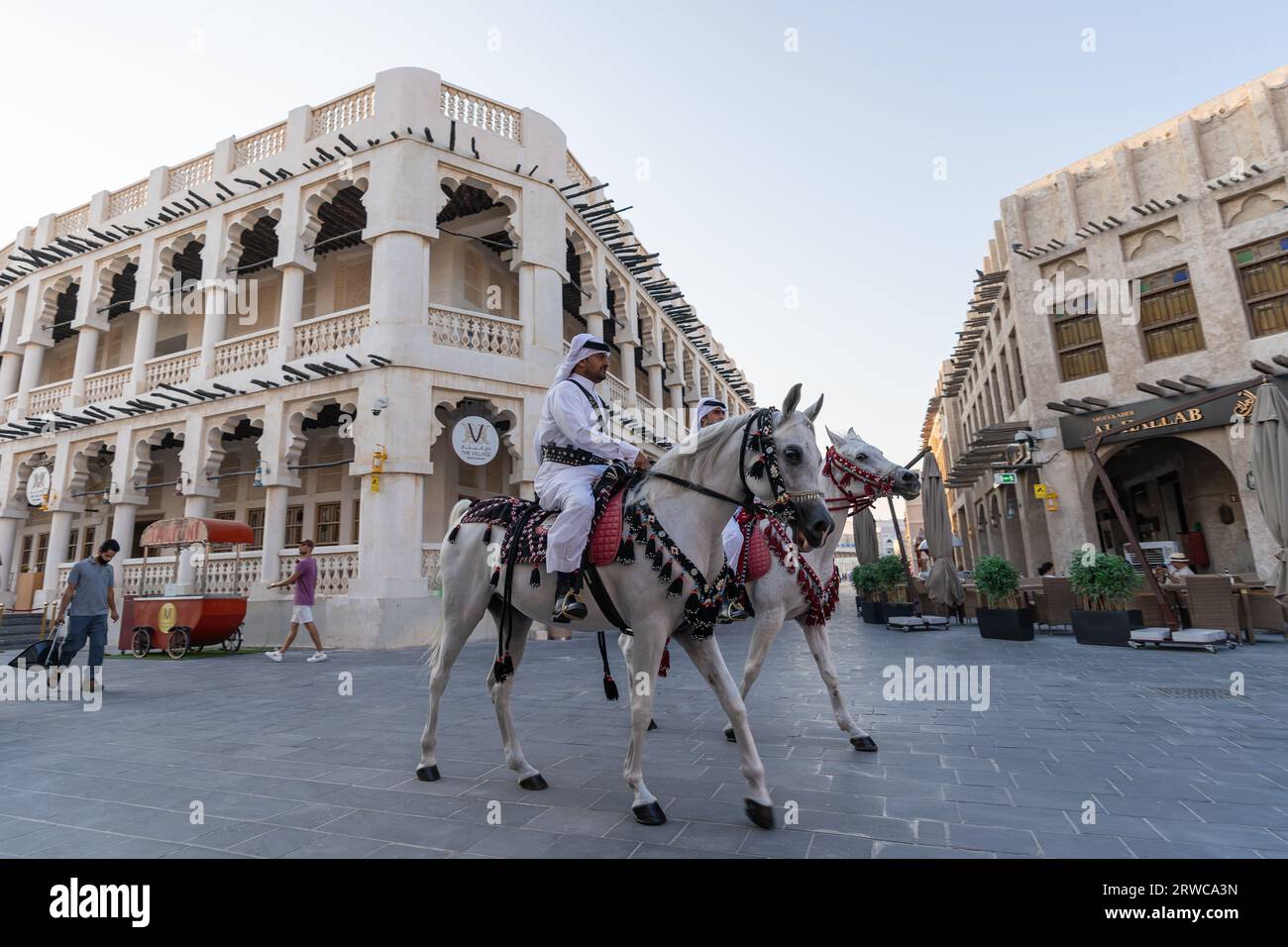 Doha, Katar - 17. Oktober 2022: Touristenpolizisten in traditioneller katarischer Kleidung patrouillieren auf dem Fußweg im Souq Wakif. Stockfoto