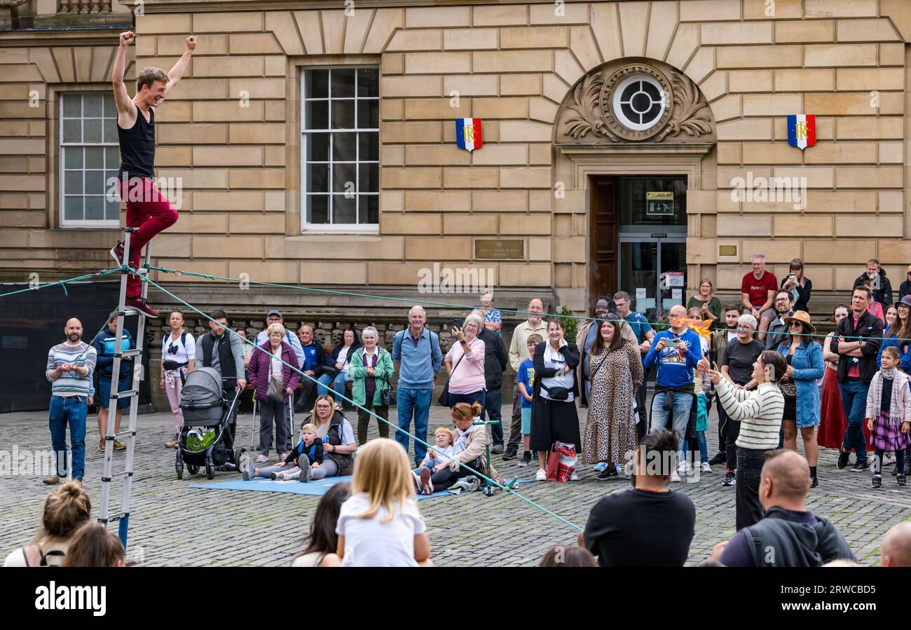 Straßenkünstler, der mit Feuerfackeln jongliert, während er auf einer Leiter steht, Edinburgh Festival Fringe, Parliament Square, Schottland, Großbritannien Stockfoto