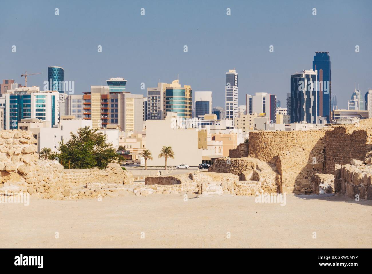 Alt und neu: Die Ruinen von Bahrain Fort, das 2300 v. Chr. datiert, gegenüber der modernen Skyline der Innenstadt von Manama Stockfoto