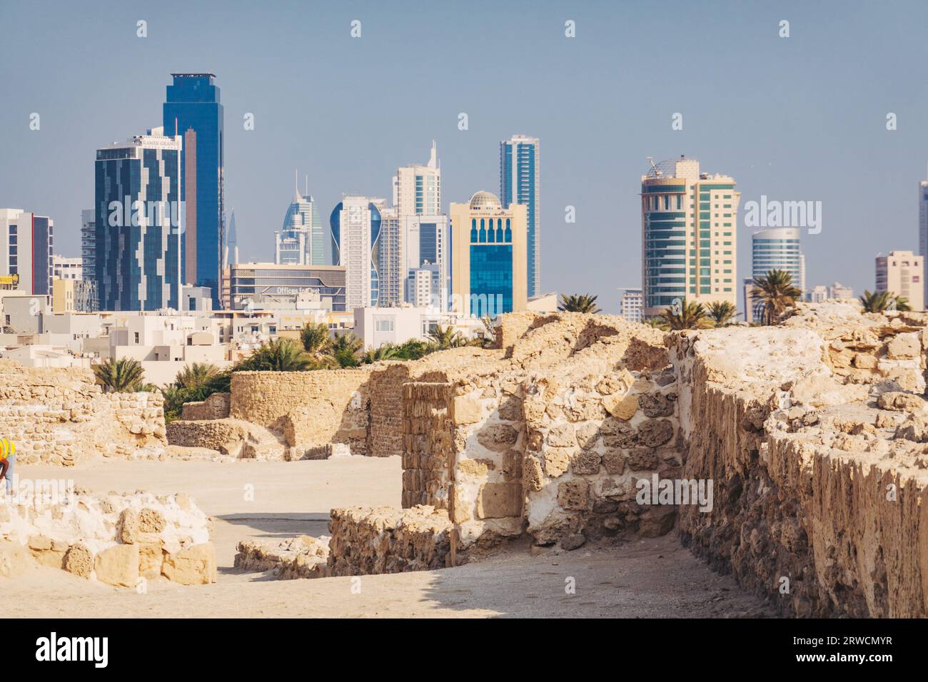 Alt und neu: Die Ruinen von Bahrain Fort, das 2300 v. Chr. datiert, gegenüber der modernen Skyline der Innenstadt von Manama Stockfoto