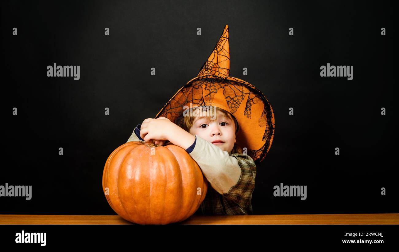 Überraschter kleiner Junge in Hexenhut mit Kürbis. Halloween-Kind mit Jack-o-Laterne. Halloween-Feiertage. Trick oder Belohnung. Vorbereitung auf Halloween Stockfoto