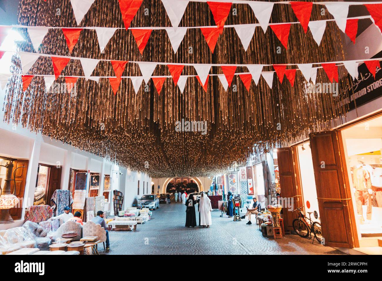 Braune Hängestangen bilden eine Kunstinstallation im Manama Souq, Bahrain. Rote und weiße Fahnen repräsentieren die Nationalfarben Stockfoto