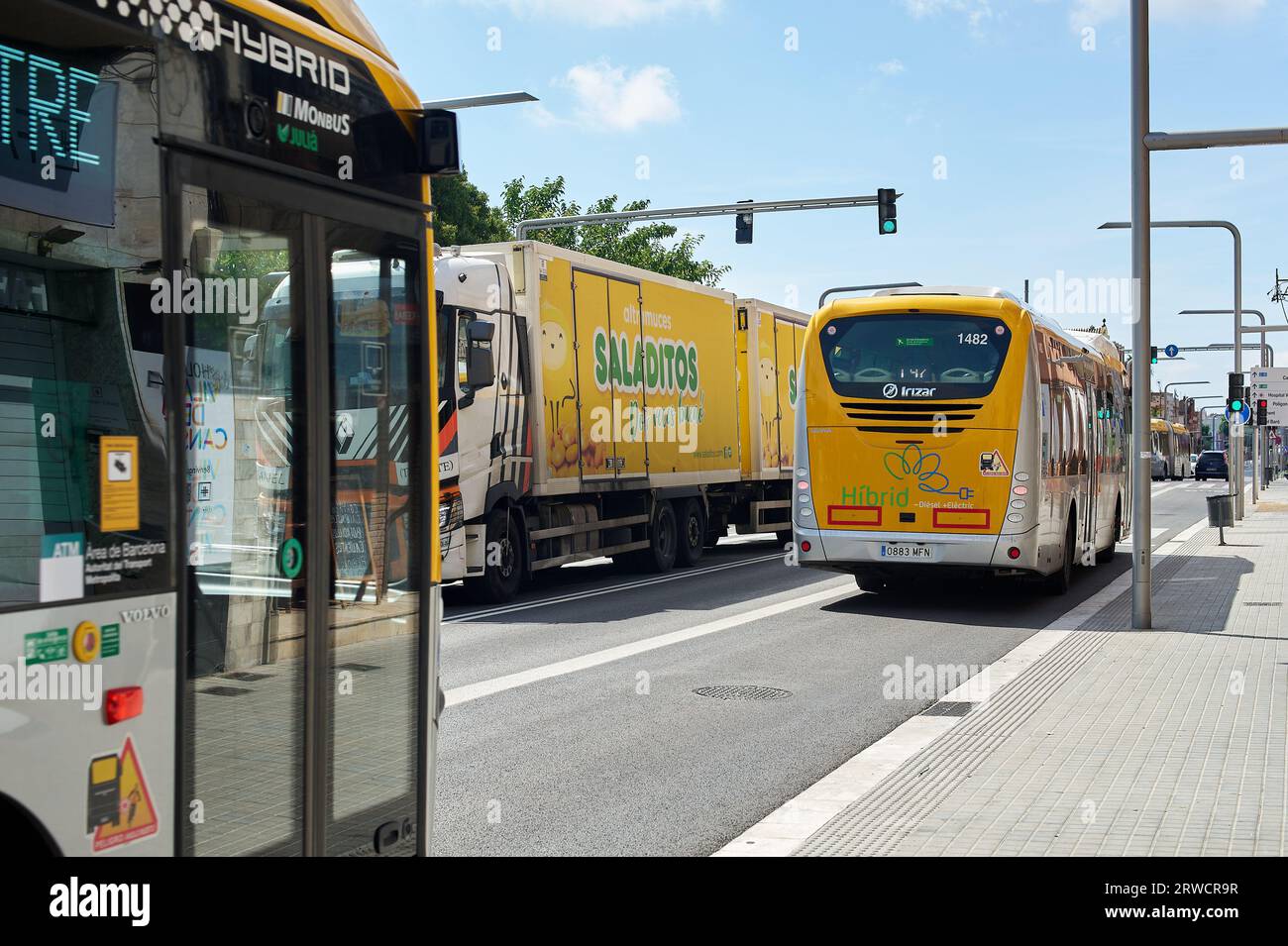 Viladecans, Spanien - 18. September 2023: Stadtbusse teilen sich die Straße mit knickgelenkten Lastkraftwagen Stockfoto