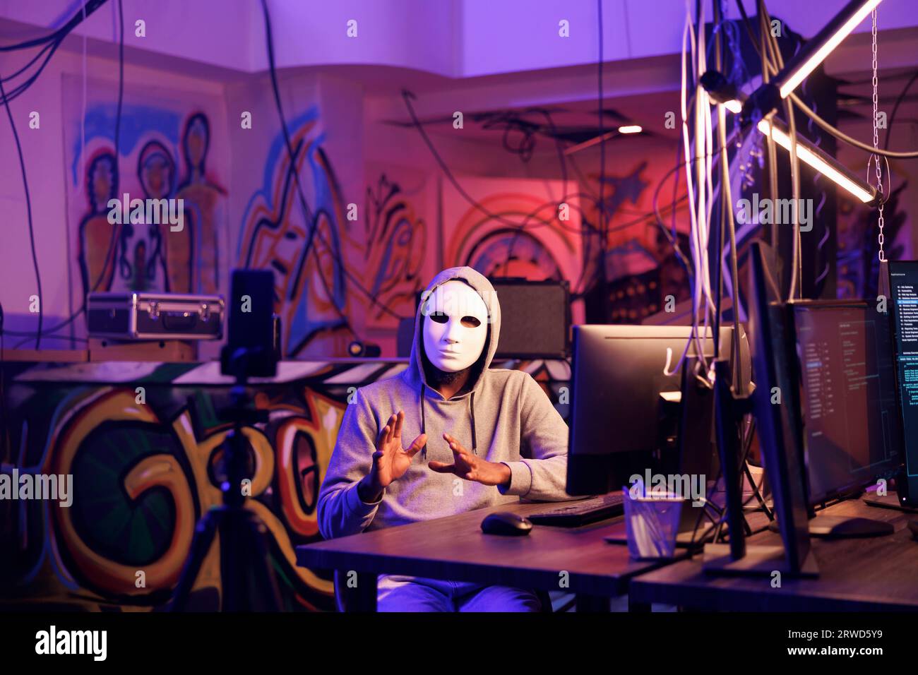 Hacker in anonymer Maske Live-Streaming illegale Online-Aktivitäten auf Smartphone für Dark Web. Kriminelle Aufzeichnung von Bedrohungen auf Mobiltelefonen und Verletzung von Datenschutzdaten im Versteck Stockfoto