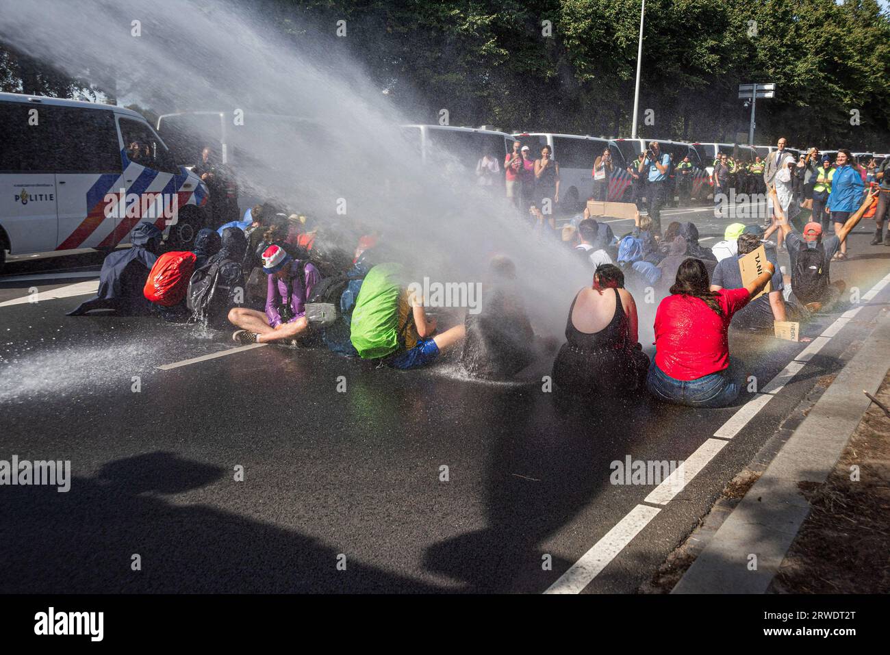 Den Haag, Niederlande. September 2023. Die Klimaaktivisten der Extinction Rebellion werden während der gewaltfreien Sitzdemonstration mit Wasserkanon besprüht. Die Extinction Rebellion organisierte am achten Tag in Folge eine Blockade auf der Autobahn A12 in den Haag, trotz eines Verbots der Gemeinde. Die A12-Blockade begann um zwölf Uhr mittags und endete zwei Stunden später. Am ersten Tag der Veranstaltung, letzten Samstag, sahen Tausende von Klimaaktivisten. Die Nummer war heute Nachmittag deutlich geringer. Einige hundert Demonstranten teilten sich in mehrere Gruppen entlang der Utrechtsebaan auf. Fast so Stockfoto