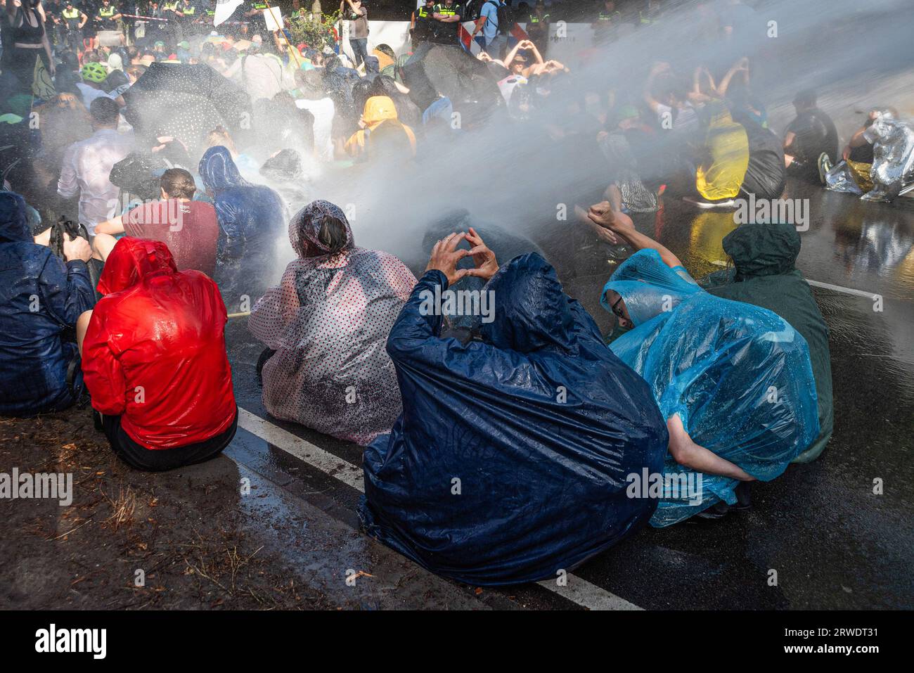 Den Haag, Niederlande. September 2023. Die Klimaaktivisten der Extinction Rebellion werden während der gewaltfreien Sitzdemonstration mit Wasserkanon besprüht. Die Extinction Rebellion organisierte am achten Tag in Folge eine Blockade auf der Autobahn A12 in den Haag, trotz eines Verbots der Gemeinde. Die A12-Blockade begann um zwölf Uhr mittags und endete zwei Stunden später. Am ersten Tag der Veranstaltung, letzten Samstag, sahen Tausende von Klimaaktivisten. Die Nummer war heute Nachmittag deutlich geringer. Einige hundert Demonstranten teilten sich in mehrere Gruppen entlang der Utrechtsebaan auf. Fast so Stockfoto