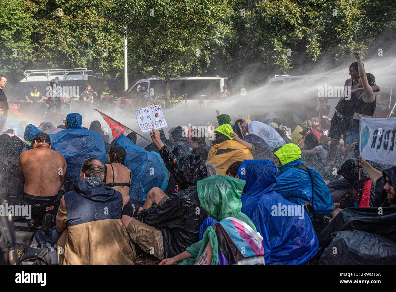 Den Haag, Niederlande. September 2023. Die Klimaaktivisten der Extinction Rebellion werden während der gewaltfreien Sitzdemonstration mit Wasserkanon besprüht. Die Extinction Rebellion organisierte am achten Tag in Folge eine Blockade auf der Autobahn A12 in den Haag, trotz eines Verbots der Gemeinde. Die A12-Blockade begann um zwölf Uhr mittags und endete zwei Stunden später. Am ersten Tag der Veranstaltung, letzten Samstag, sahen Tausende von Klimaaktivisten. Die Nummer war heute Nachmittag deutlich geringer. Einige hundert Demonstranten teilten sich in mehrere Gruppen entlang der Utrechtsebaan auf. Fast so Stockfoto