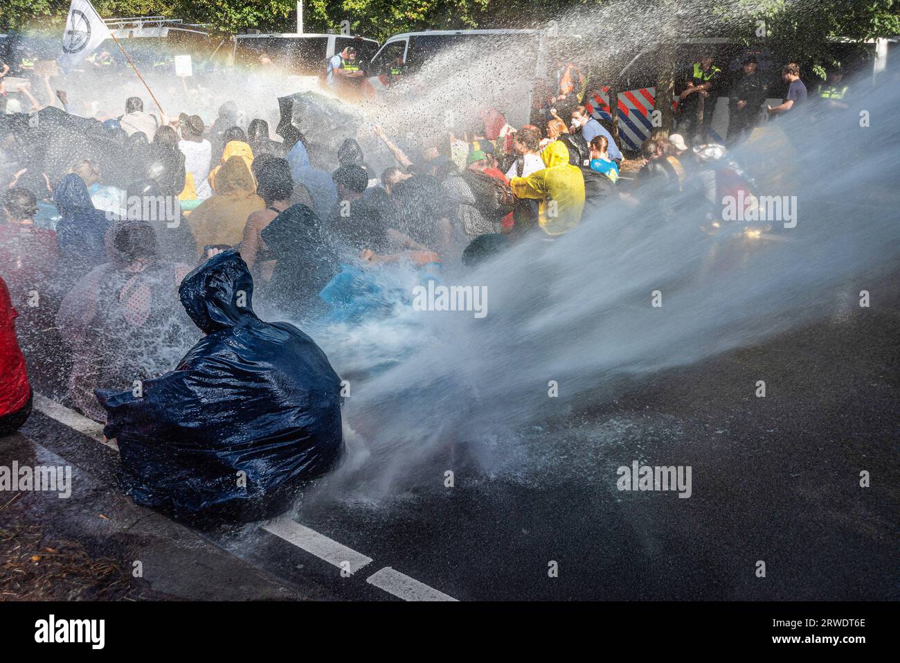 Den Haag, Niederlande. September 2023. Die Klimaaktivisten der Extinction Rebellion werden während der gewaltfreien Sitzdemonstration mit Wasserkanon besprüht. Die Extinction Rebellion organisierte am achten Tag in Folge eine Blockade auf der Autobahn A12 in den Haag, trotz eines Verbots der Gemeinde. Die A12-Blockade begann um zwölf Uhr mittags und endete zwei Stunden später. Am ersten Tag der Veranstaltung, letzten Samstag, sahen Tausende von Klimaaktivisten. Die Nummer war heute Nachmittag deutlich geringer. Einige hundert Demonstranten teilten sich in mehrere Gruppen entlang der Utrechtsebaan auf. Fast so Stockfoto