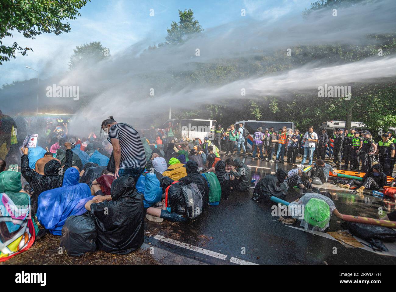 Den Haag, Niederlande. September 2023. Die Klimaaktivisten der Extinction Rebellion werden während der gewaltfreien Sitzdemonstration mit Wasserkanon besprüht. Die Extinction Rebellion organisierte am achten Tag in Folge eine Blockade auf der Autobahn A12 in den Haag, trotz eines Verbots der Gemeinde. Die A12-Blockade begann um zwölf Uhr mittags und endete zwei Stunden später. Am ersten Tag der Veranstaltung, letzten Samstag, sahen Tausende von Klimaaktivisten. Die Nummer war heute Nachmittag deutlich geringer. Einige hundert Demonstranten teilten sich in mehrere Gruppen entlang der Utrechtsebaan auf. Fast so Stockfoto
