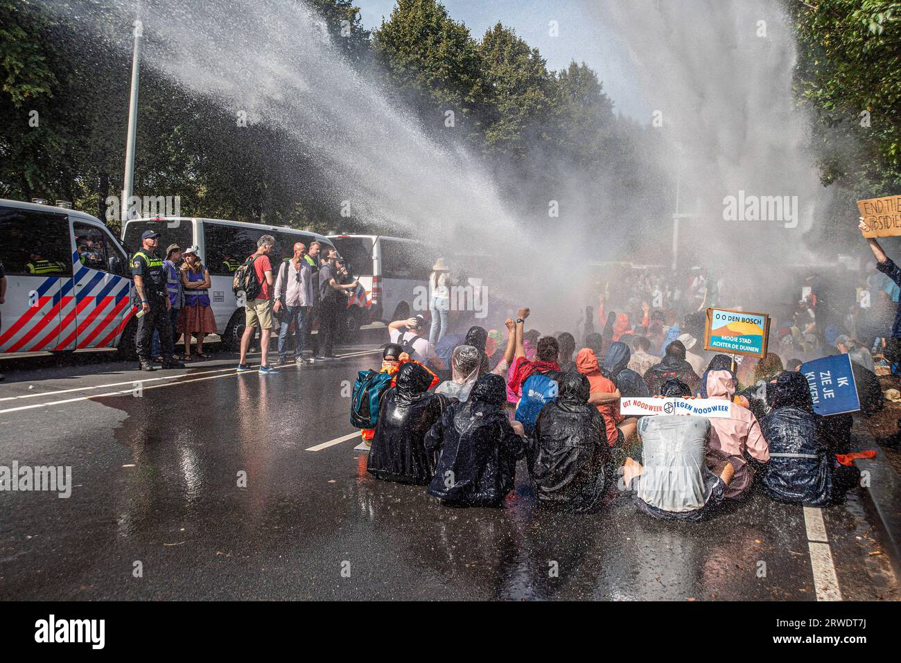 Den Haag, Niederlande. September 2023. Die Klimaaktivisten der Extinction Rebellion werden während der gewaltfreien Sitzdemonstration mit Wasserkanon besprüht. Die Extinction Rebellion organisierte am achten Tag in Folge eine Blockade auf der Autobahn A12 in den Haag, trotz eines Verbots der Gemeinde. Die A12-Blockade begann um zwölf Uhr mittags und endete zwei Stunden später. Am ersten Tag der Veranstaltung, letzten Samstag, sahen Tausende von Klimaaktivisten. Die Nummer war heute Nachmittag deutlich geringer. Einige hundert Demonstranten teilten sich in mehrere Gruppen entlang der Utrechtsebaan auf. Fast so Stockfoto